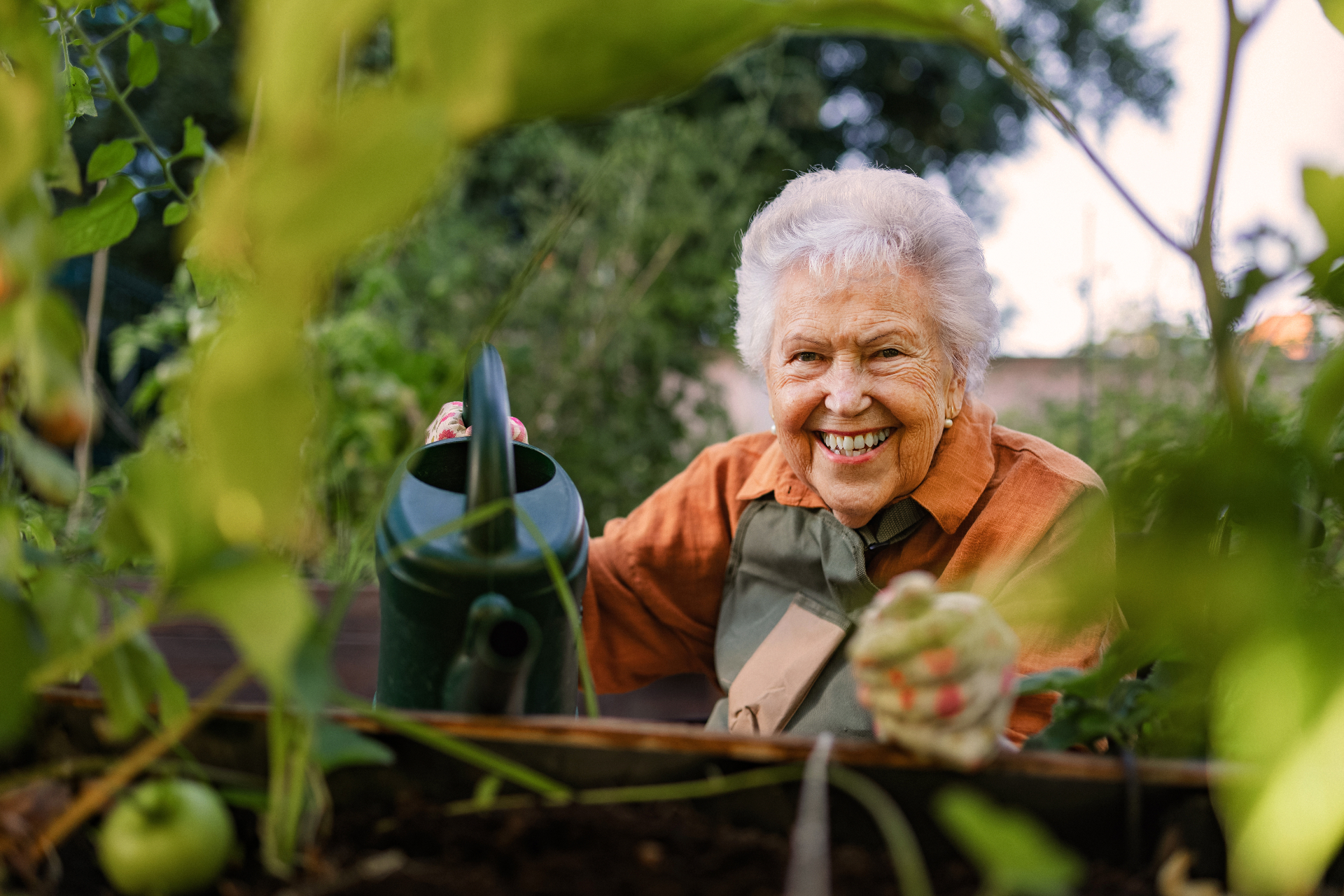 Lächelnde Seniorin mit Gießkanne im Garten